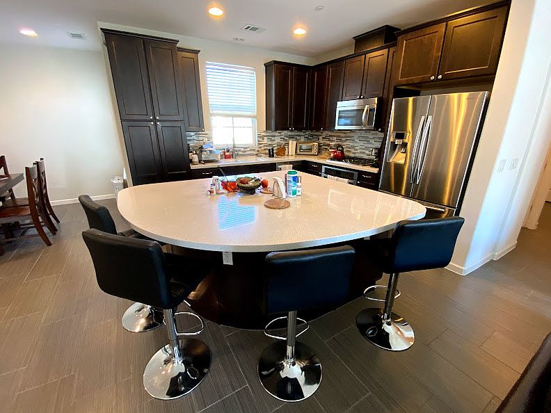 Open concept kitchen with huge island with modern kitchen appliances (fridge, microwave, oven, dishwasher, toaster oven).
