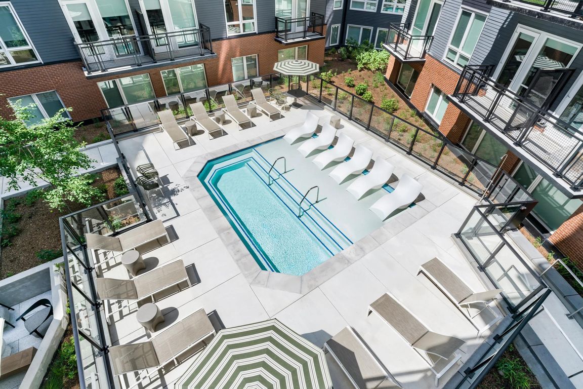 Courtyard pool with in-water loungers, sun seating, and surrounding balconies creating a social outdoor setting for warm-weather downtime.
