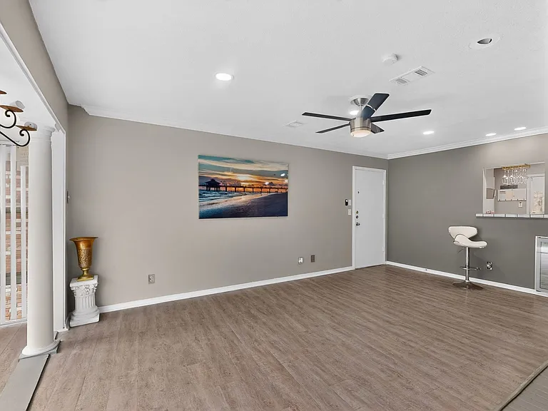 Bright living room with a ceiling fan, situated beside the sunroom; perfect for relaxation and comfort.