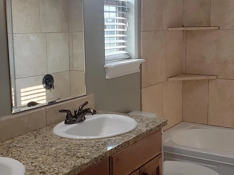 Dual sinks, granite counters and tiled floors in owner's bath.
