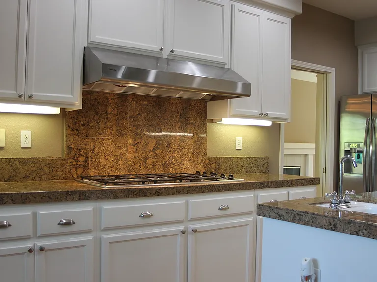 Chef's Kitchen with gas stove, granite counters, white cabinets, center island with utility sink, ample storage