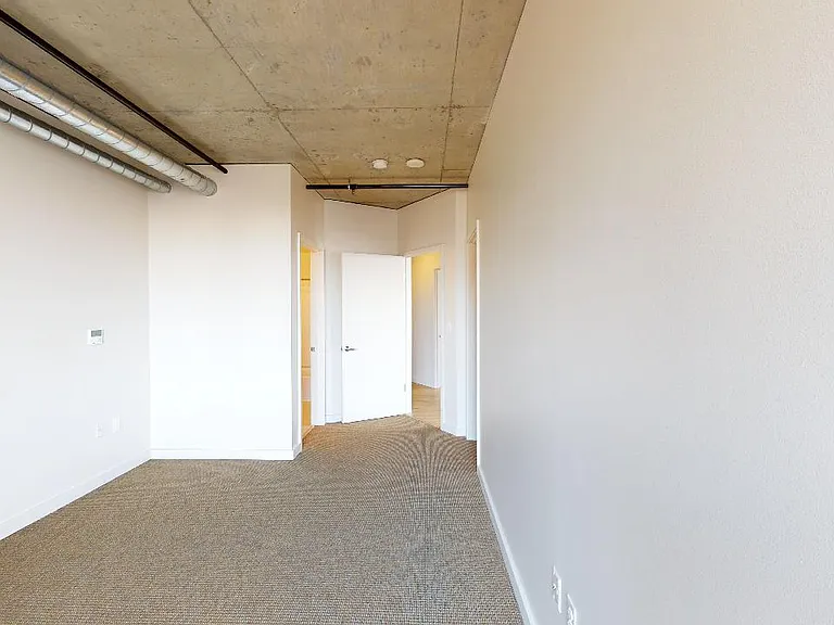 Spacious apartment bedroom with plush carpet flooring.