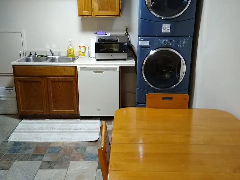 Kitchen looking South. Stainless steel sink, Dishwasher, Washer/Dryer stack, Table & chairs, storage above sink