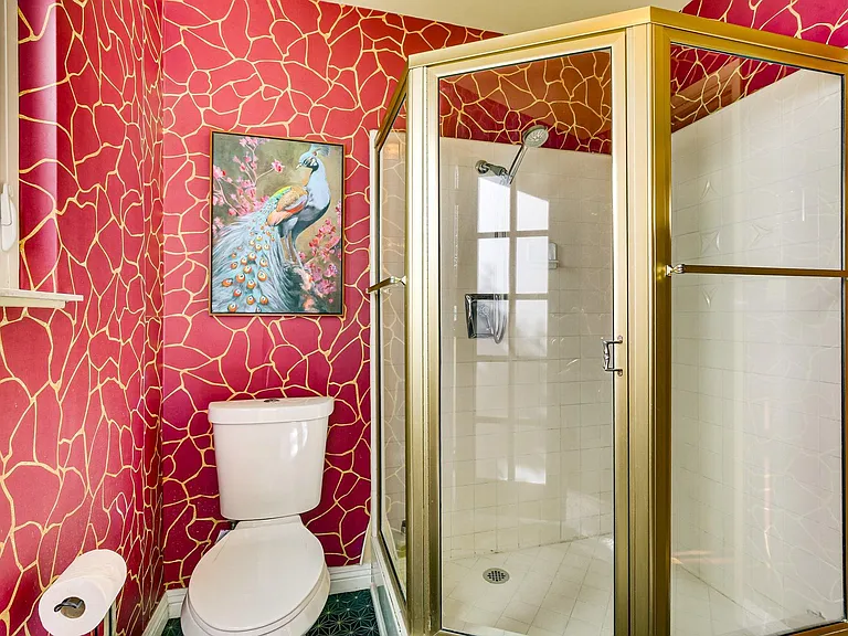 Bathroom with a glass-enclosed corner shower, window for ventilation, and bold patterned wall finish with wall art.