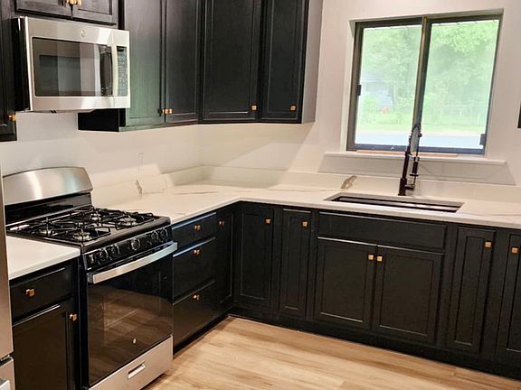 Kitchen featuring black cabinets Stainless Steel Appliances, Quartz Stone countertops a Gas Range, Micorwave Vent Hood