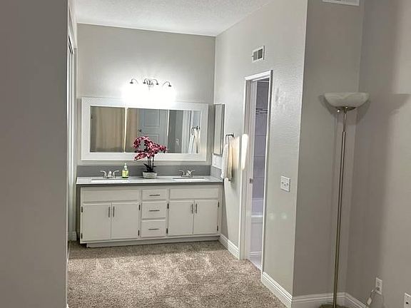 1st Master Bedroom. Comes unfurnished with the exception of torch lamps in 3 corners which can be removed. Ceiling light and fan on wall switch. En suite bathroom features two sinks accessible from bedroom with toilet and bath behind a door. Mirrored clos