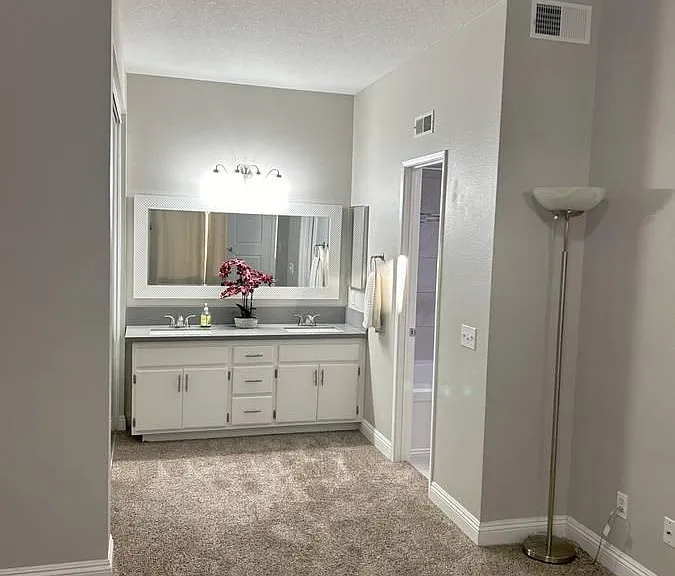 1st Master Bedroom. Comes unfurnished with the exception of torch lamps in 3 corners which can be removed. Ceiling light and fan on wall switch. En suite bathroom features two sinks accessible from bedroom with toilet and bath behind a door. Mirrored clos