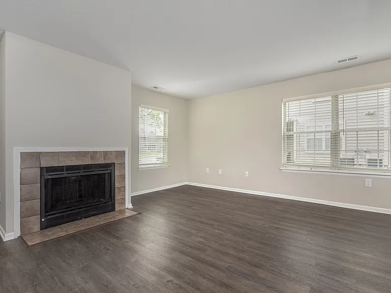 The Glenmount's bright, open living room features a wood burning fireplace and wood-plank inspired flooring.