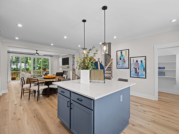 A modern and open-concept kitchen with a central island, pendant lighting, and artwork on the walls,