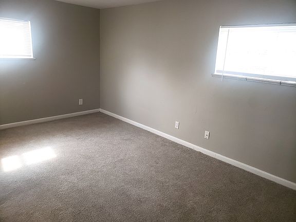 Bright and inviting room with plush carpet, large windows, and neutral walls perfect for personalization.