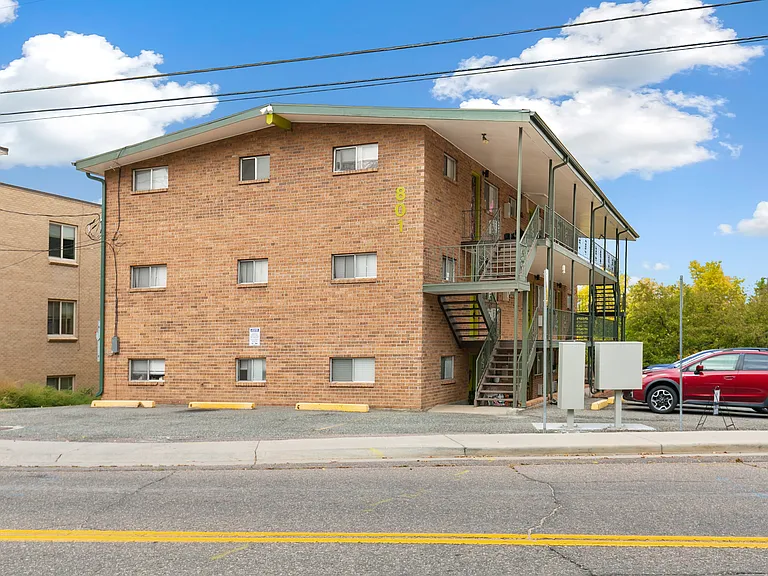 Charming brick apartment building with modern exterior stairs, set against a bright blue sky.