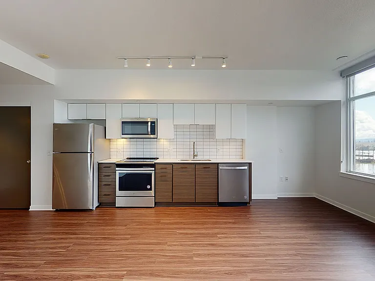 Apartment Kitchen with Stainless Steel Appliances, Quartz-style countertops and Wood-Style Flooring.