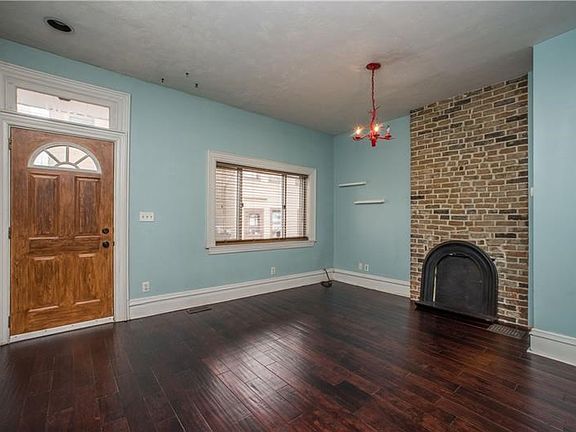 You enter the home into a bright living room with beautiful hardwood floors and decorative fireplace.