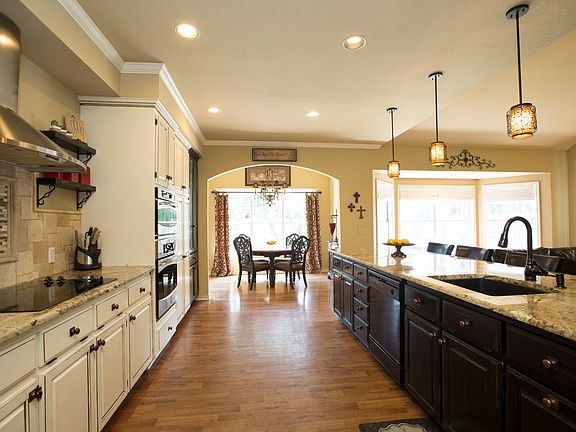 View from Kitchen into Family Room reveals trend-setting pendant lighting, oil rubbed bronze pull down faucet, large breakfast bar and charming arch opening to Breakfast Nook.
