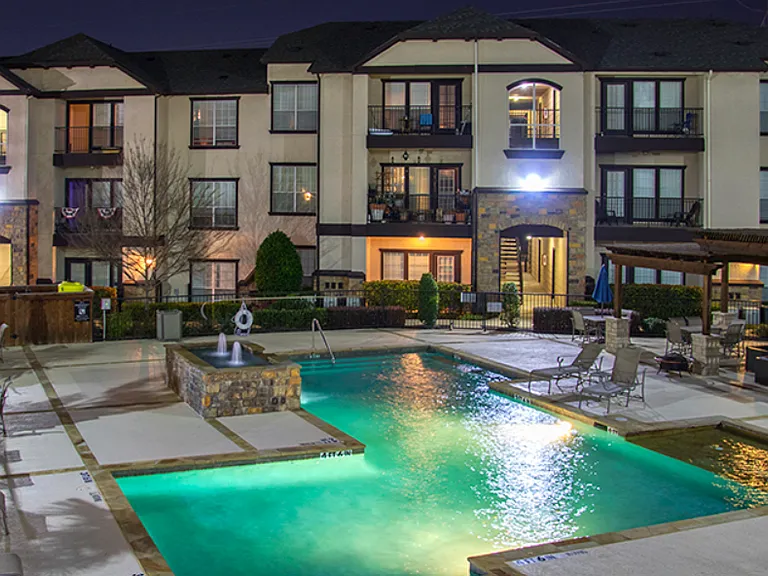 Resort-style swimming pool illuminated at night with relaxing ambiance
