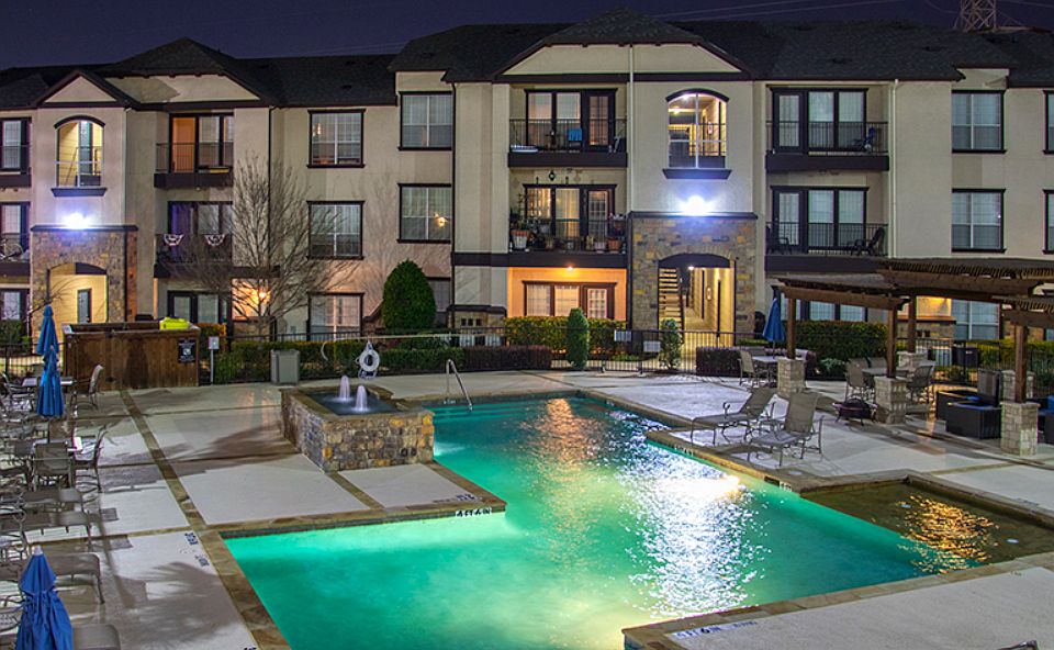 Resort-style swimming pool illuminated at night with relaxing ambiance