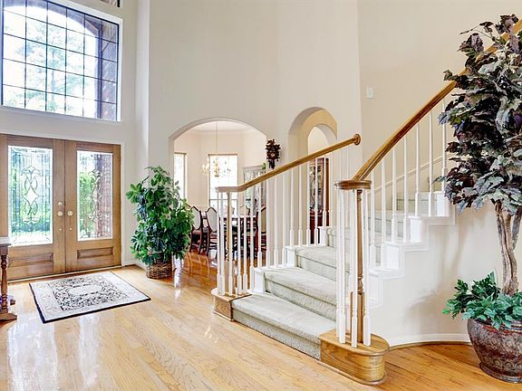 View of the foyer showing the curved stairs and the elegant double pannel glass door. You can also see the dining room at the back of the photo.