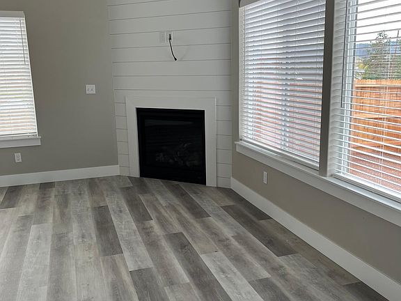 Den with gas fireplace and ceiling fan and window coverings.