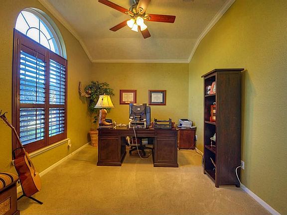 Large study with plantation shutters and crown molding.