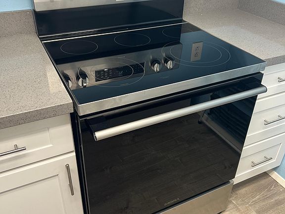 fully remodeled kitchen with newer electric range, over, dishwasher, refrigerator, ducted under cabinet range hood.