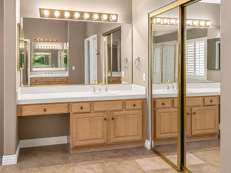 Bright vanity area with large mirrors, tile countertop, and ample storage
