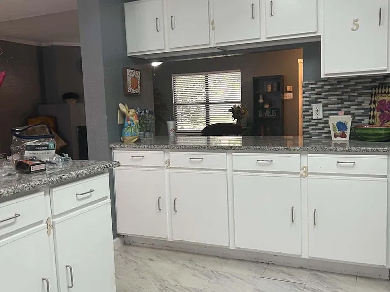 Spacious kitchen with ample white cabinetry, granite-look counters, and a breakfast bar overlooking the living area.