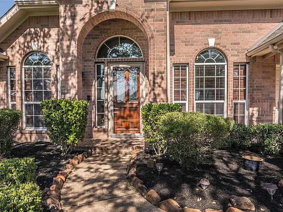 Landscaped walk leads to leaded glass door.