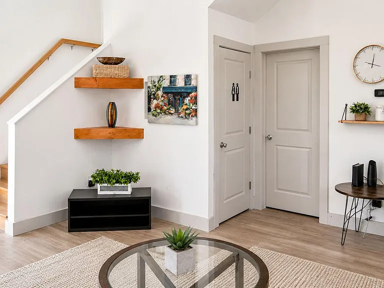 Inviting living area with wood-style flooring, stair access, and space for seating plus accent shelving and decor.