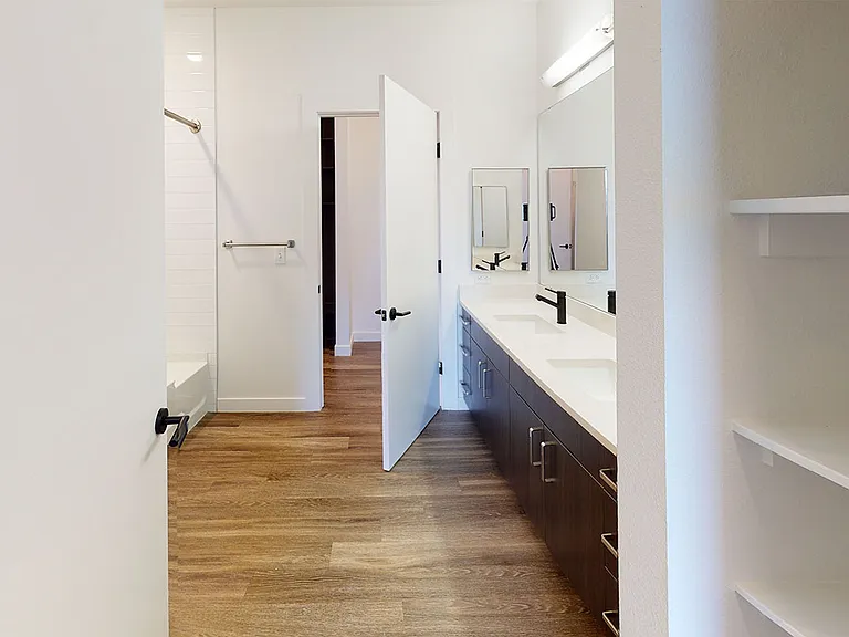 Apartment bathroom with large soaking tub, wood-style flooring and double sinks.