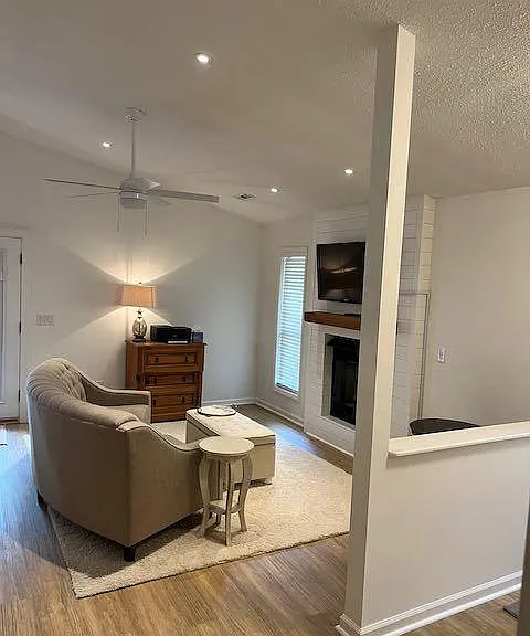 Living room with gas logs in the fireplace, flat screen television, recessed lighting and quiet ceiling fans all controlled by remote controls.