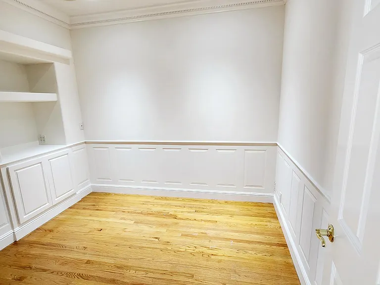 Entry to bedroom #1 with hardwood floors, walk in closet, built in cabinetry & sky light.