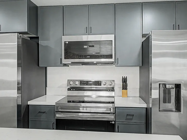 Well-equipped kitchen with stainless steel range and microwave, ample cabinet storage, and generous counter space.