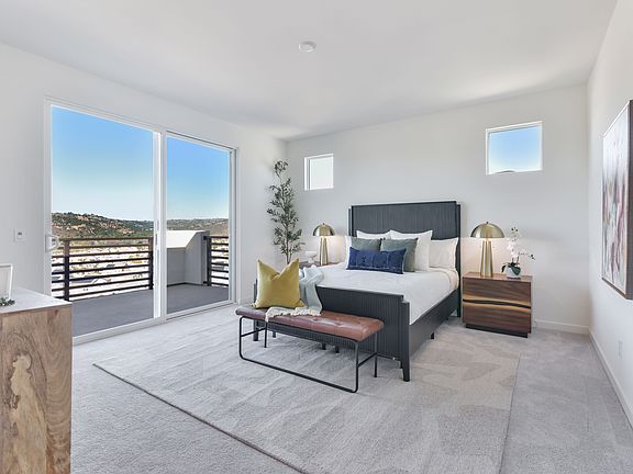 A modern and spacious bedroom with large windows offering a scenic view of the surrounding landscape