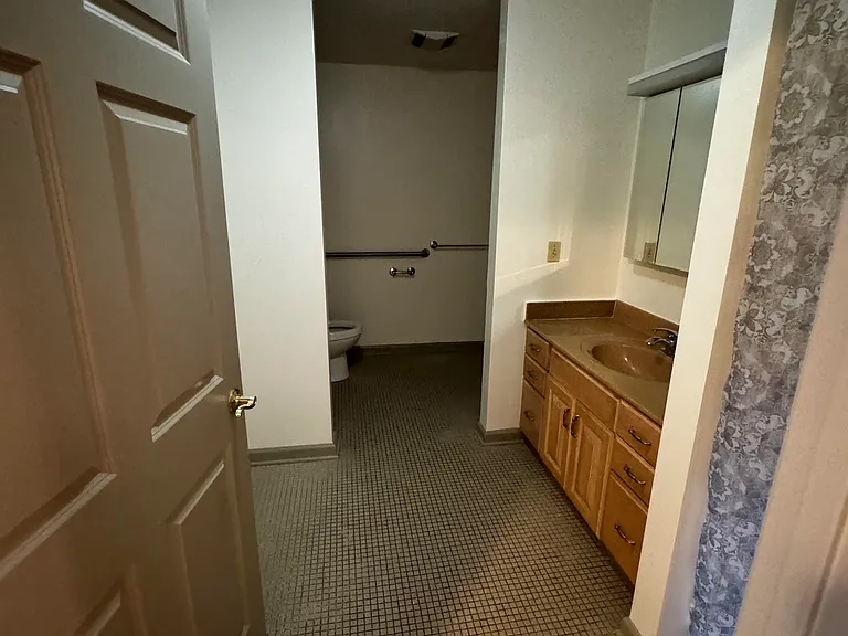 Bathroom with tile floors, mirror, sink with cabinets