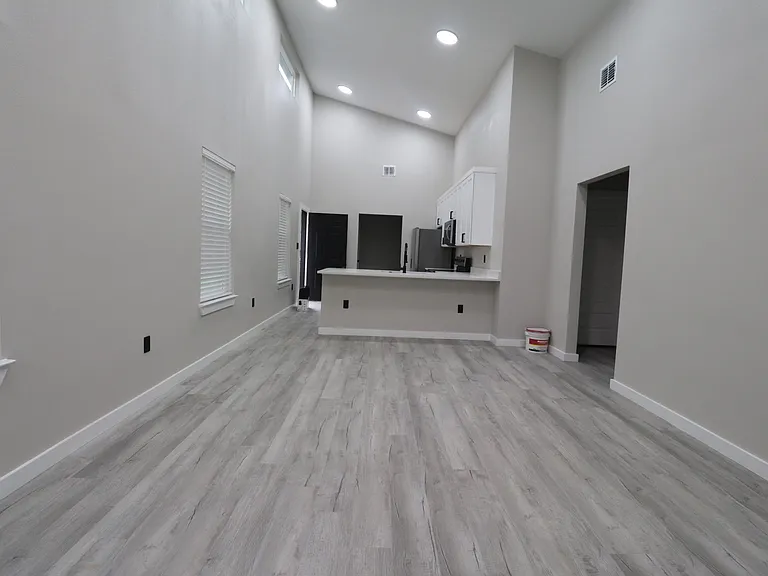 Bright open-concept living area with high ceilings, modern ceiling fan, and abundant natural light. Clean finishes and spacious layout.
