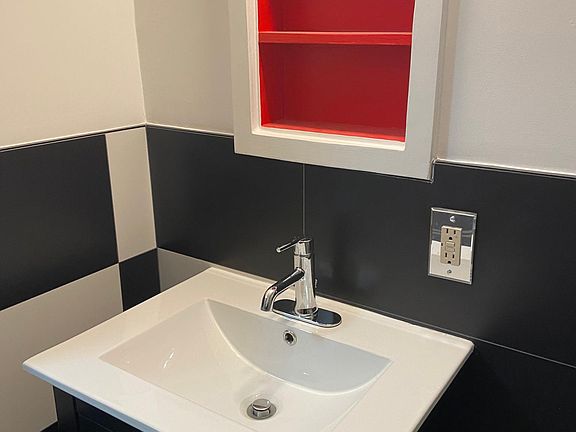 Black and white tile (walls, floor + shower), with splash of bright red cabinet! Black vanity and toilet.
