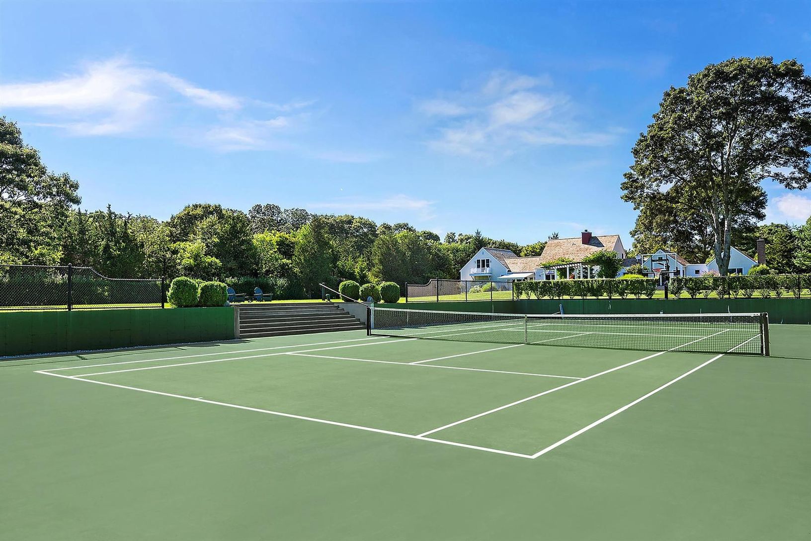 Sunken tennis court with basketball net and court lines, facing away from sun, with Sonos