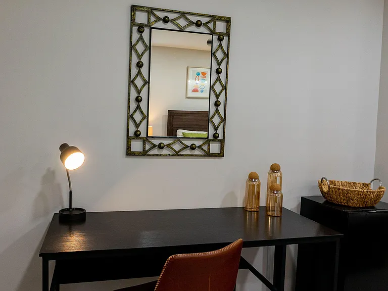 Dedicated desk nook with task lighting and a decorative wall mirror, offering a practical spot for work or study.