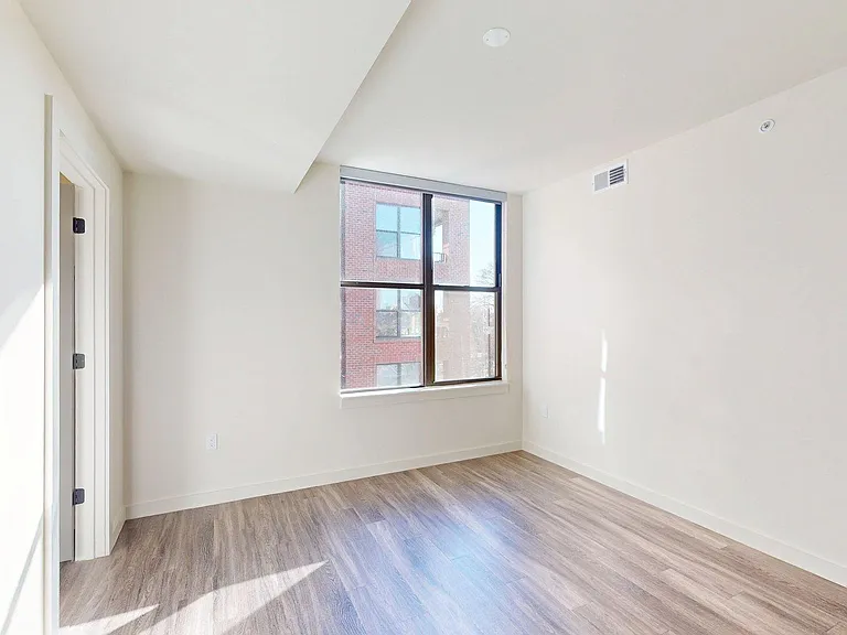 Spacious apartment bedroom with wood-style flooring.