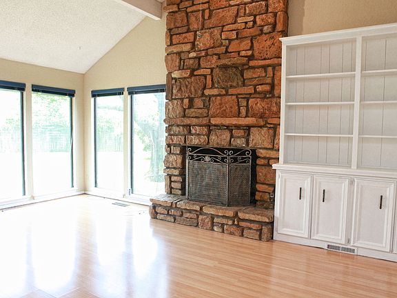 Floor to Ceiling Stone Fireplace, Built-in Bookcases and Large Windows are featured in this Living Area