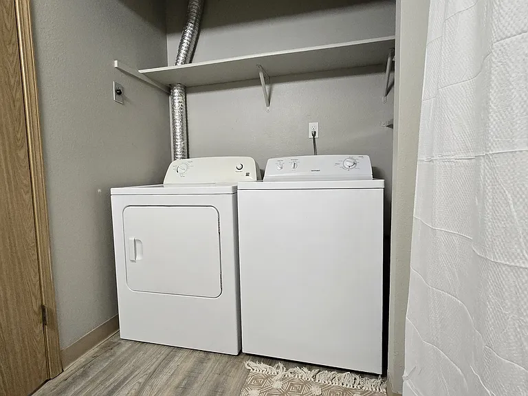 In-bathroom laundry with full-size washer and dryer, plus overhead shelving for extra storage_convenient, space-saving, and easy for everyday use.