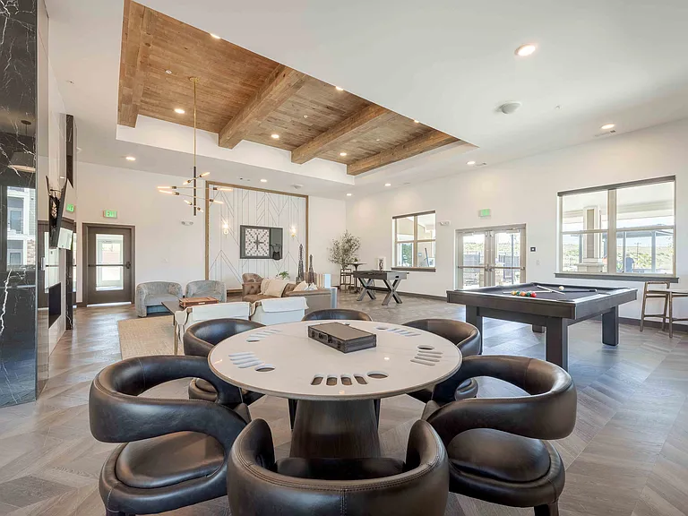 A round game table with built in storage sits alongside the billiards and foosball tables in the Garrett Parker clubhouse, creating a flexible space for resident game nights.