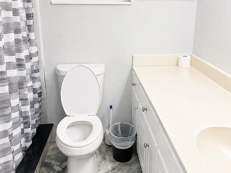 Clean full bath with a tub/shower combo, long vanity with storage, and an operable window for ventilation.
