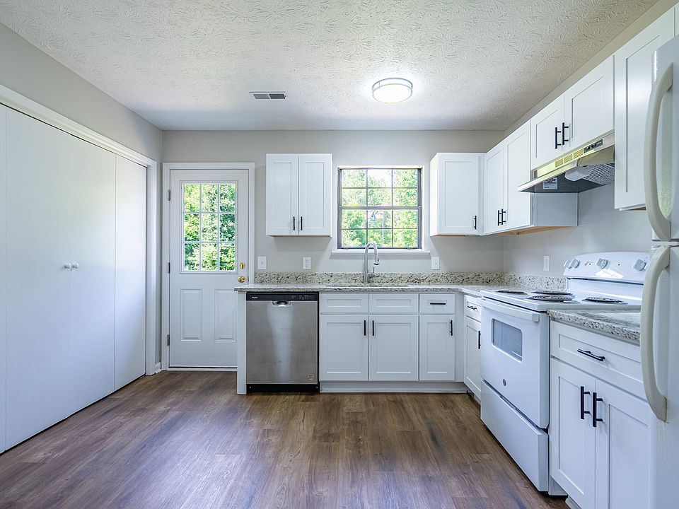 Updated kitchen with white shaker cabinets, granite countertops, dishwasher, and view of back yard