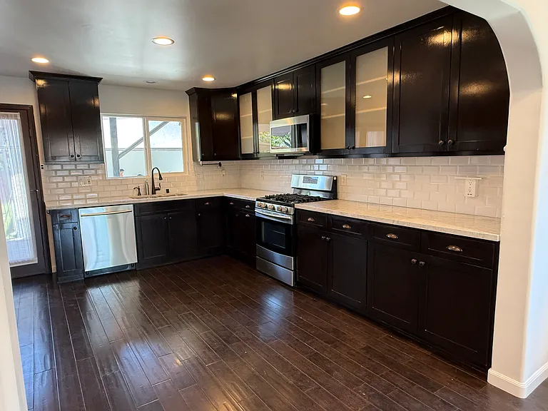 Kitchen with abundant storage, stainless steel appliances, dimmable recessed LED lighting, and views of the backyard and patio