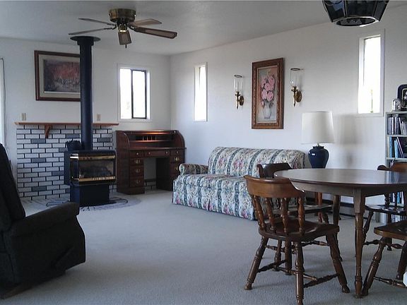 The great room is anchored by a propane fireplace, with lots of windows surrounding the room. 