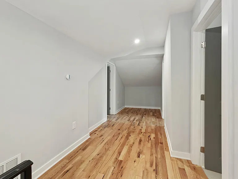 Finished upper-level flex space with hardwood floors, recessed lighting, and adjacent doors for storage or extra rooms.