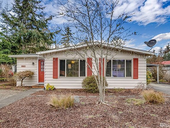 The front door is seen on the left.  The two front windows span the large living room.