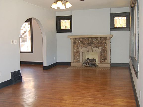 Stain glass windows flank gas log fireplace in living room.