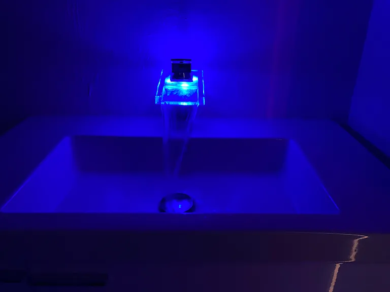 Floating bathroom vanity with illuminated faucet.